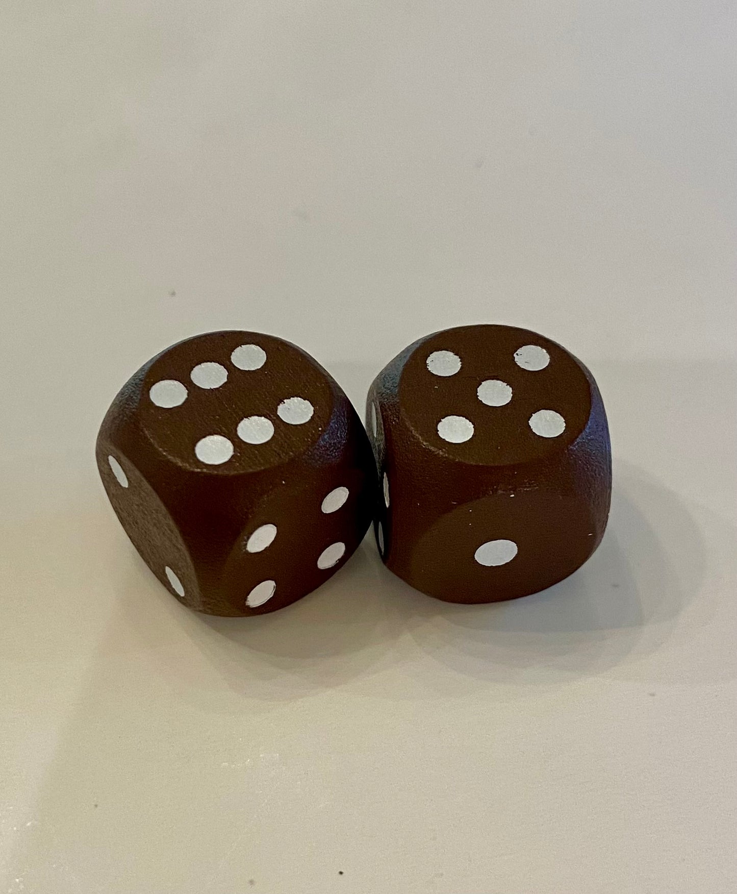 Two brown wooden dice with white dots on a white background
